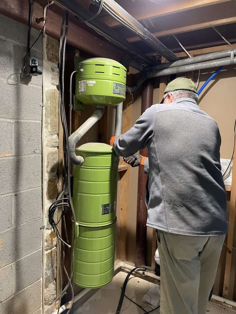 Technician repairing a central vacuum power unit in a residential utility room